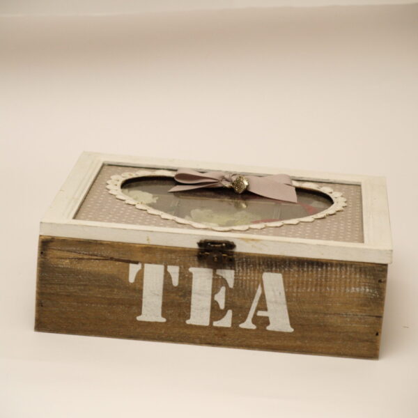 Pelēka tējas kaste ar sirds formas lodziņu.