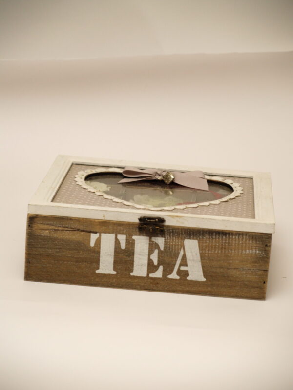 Pelēka tējas kaste ar sirds formas lodziņu.